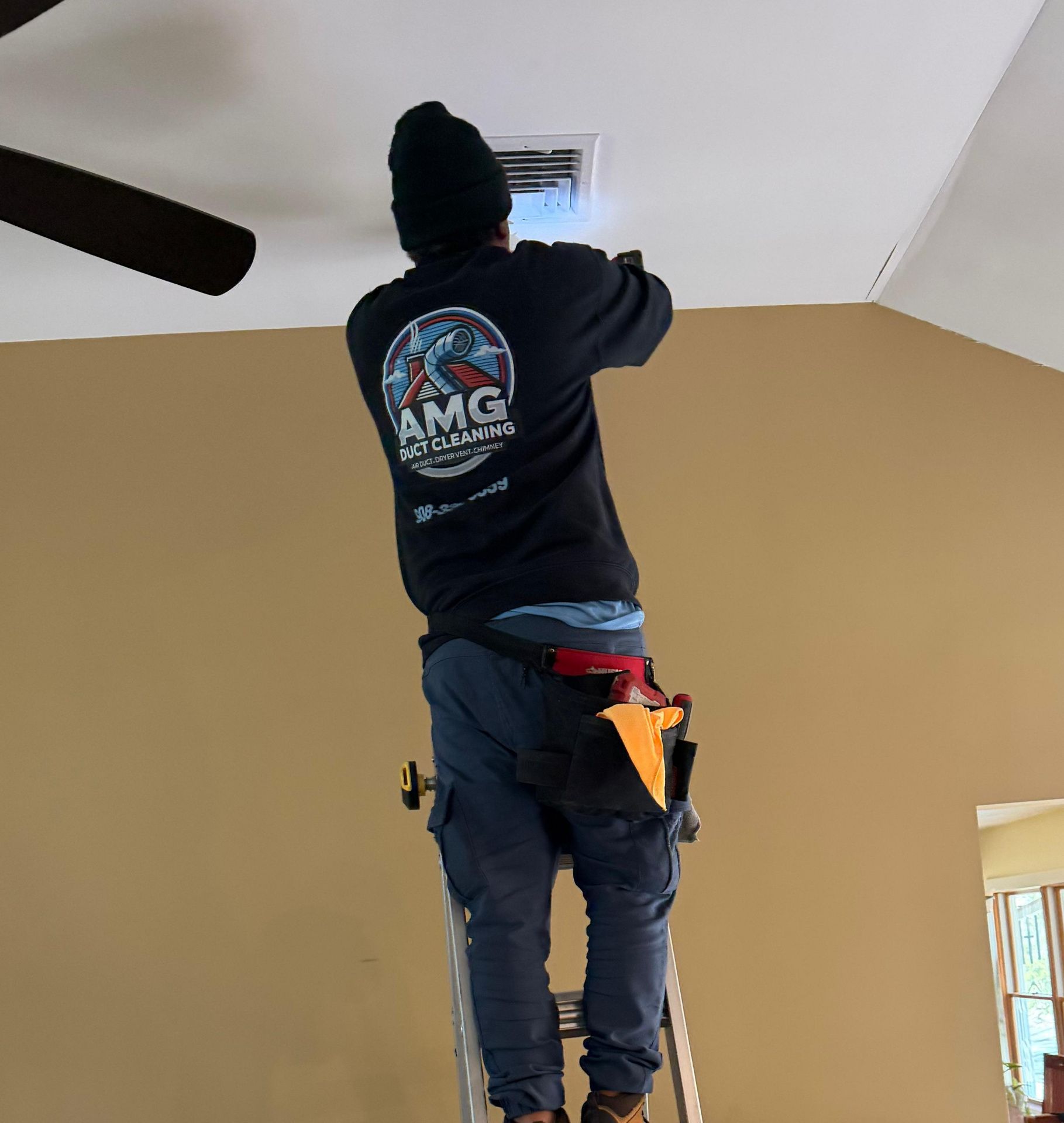 AMG technician on a step ladder working a ceiling supply register