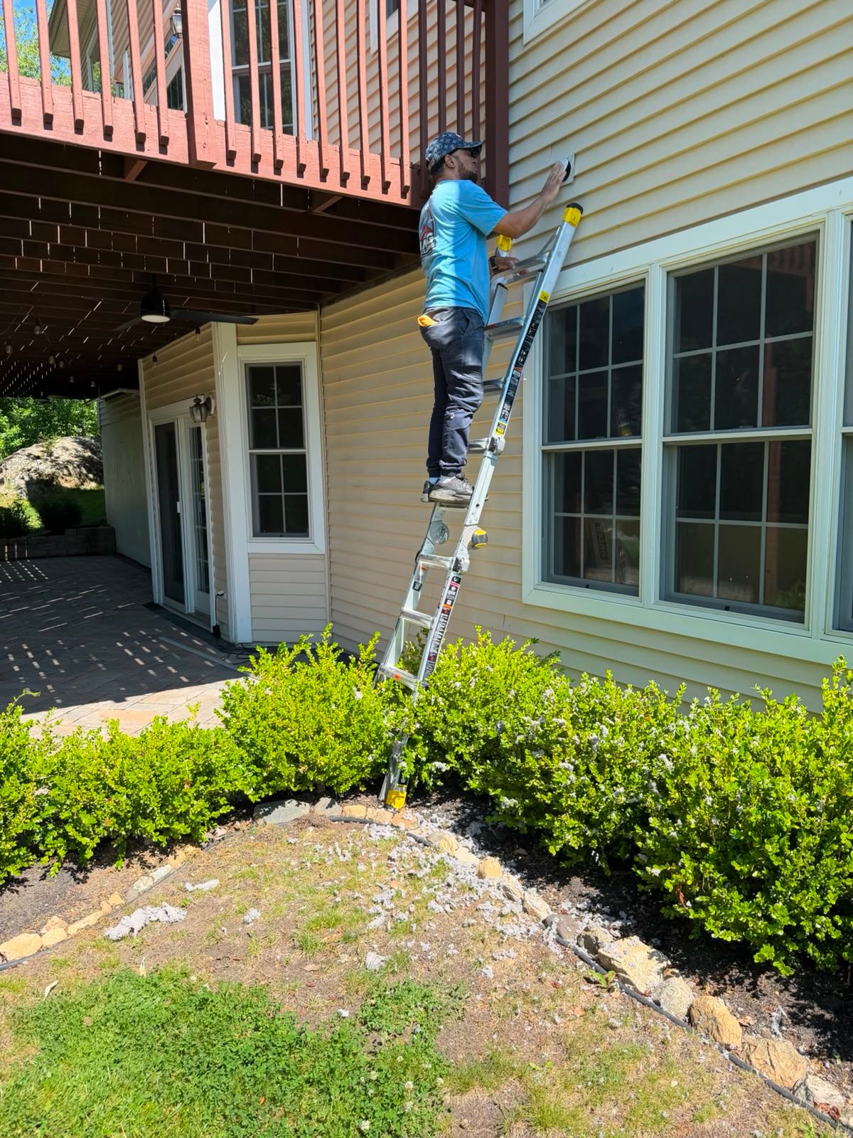 AMG technician on a ladder fitting an exterior wall vent