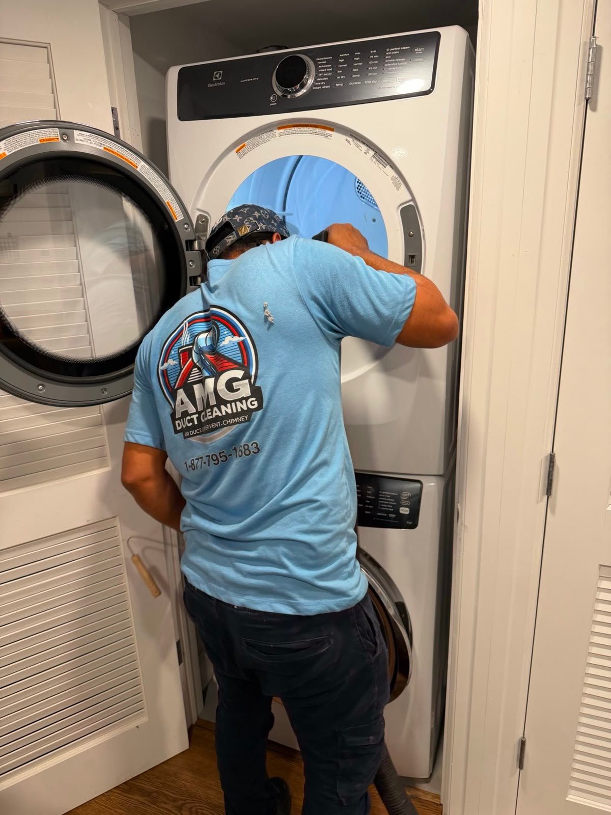 An AMG technician in a light blue AMG shirt cleaning a home dryer vent