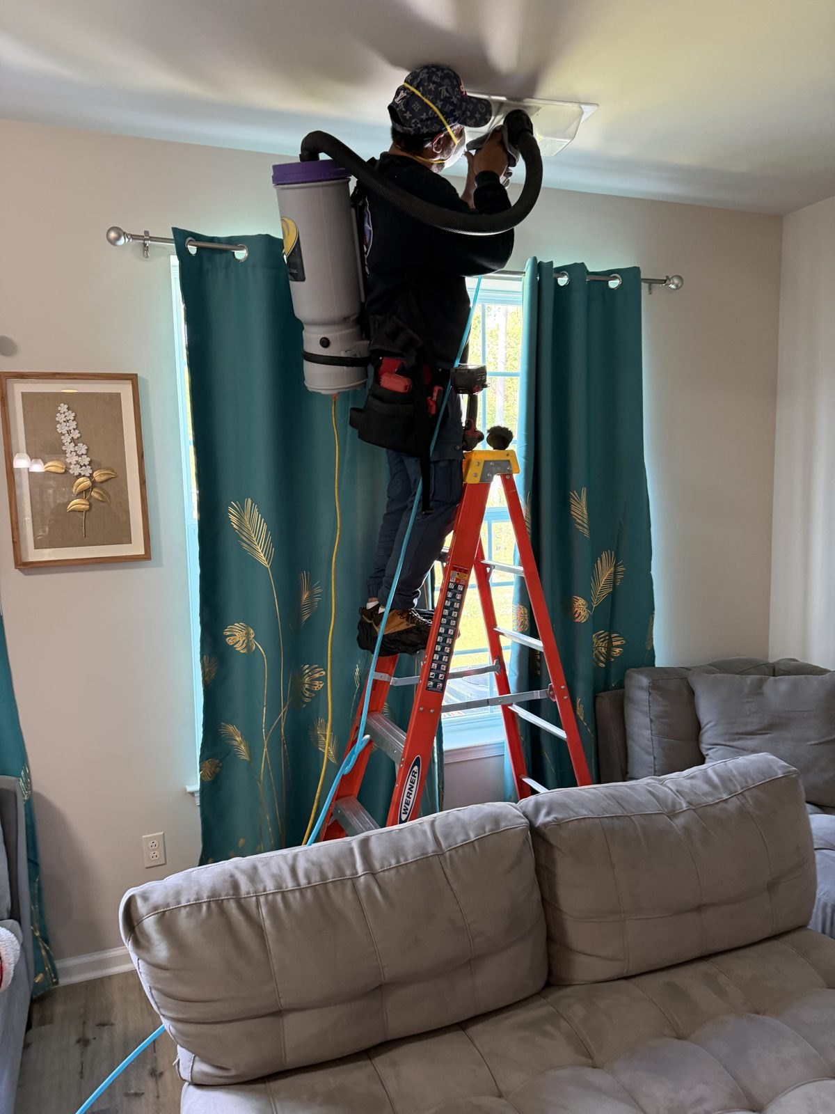 An AMG technician cleaning a ceiling vent from a ladder. AMG at work for homes in Kenilworth, New Jersey.
