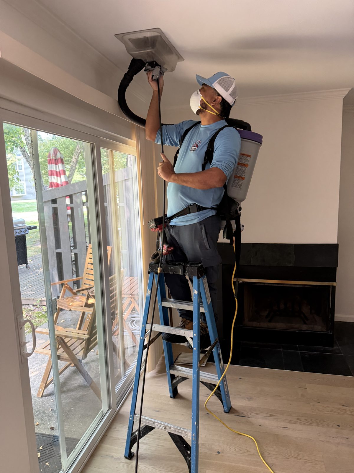 An AMG technician cleaning a ceiling vent with a HEPA vacuum. AMG at work for homes in South Orange, New Jersey.