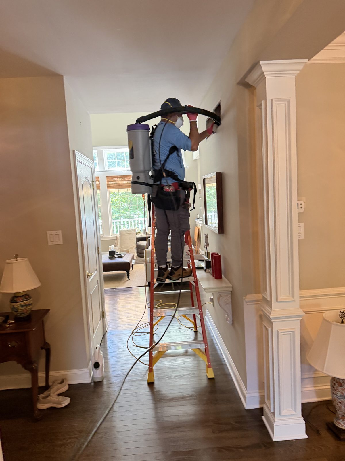 An AMG technician cleaning ducts in a home hallway