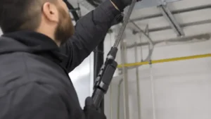 A technician in a clean work uniform using a high-powered vacuum hose attached to a supply duct register in a freshly bu
