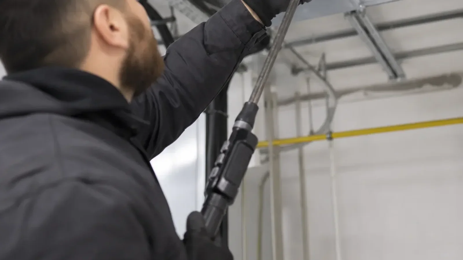 A technician in a clean work uniform using a high-powered vacuum hose attached to a supply duct register in a freshly bu